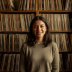 Portrait of Nadia, editor, smiling in front of shelves of records